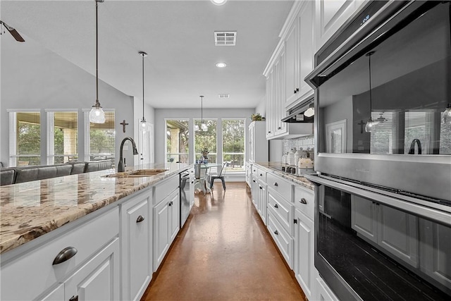 kitchen with sink, hanging light fixtures, light stone countertops, concrete flooring, and white cabinetry