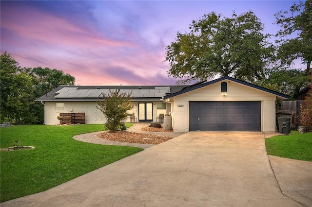 single story home featuring a lawn, solar panels, and a garage