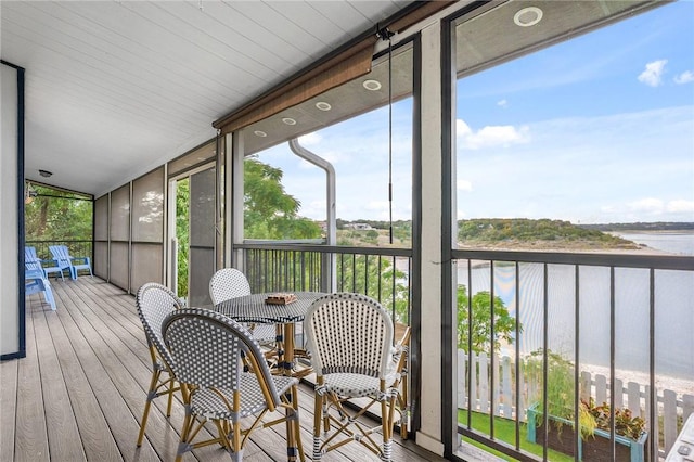 sunroom featuring a water view