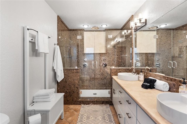 bathroom with a textured ceiling, tile patterned flooring, walk in shower, and vanity