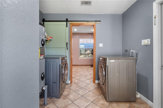 laundry area featuring light tile patterned floors, a barn door, and washer and clothes dryer