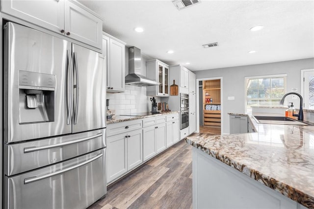 kitchen with white cabinets, dark wood-type flooring, wall chimney exhaust hood, and stainless steel appliances