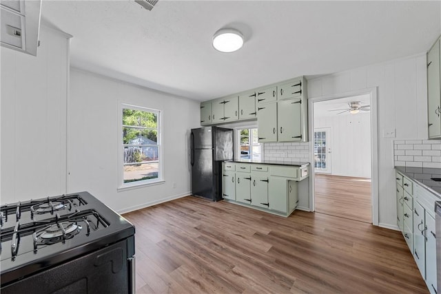 kitchen with decorative backsplash, light wood-type flooring, green cabinets, and black appliances