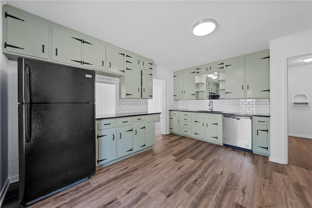 kitchen featuring backsplash, black fridge, stainless steel dishwasher, sink, and wood-type flooring