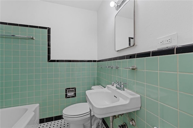 bathroom featuring a washtub, toilet, sink, and tile walls