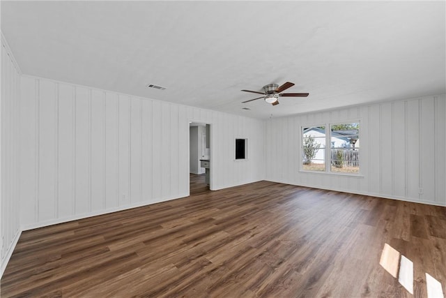 unfurnished room featuring ceiling fan, wood walls, and dark hardwood / wood-style flooring