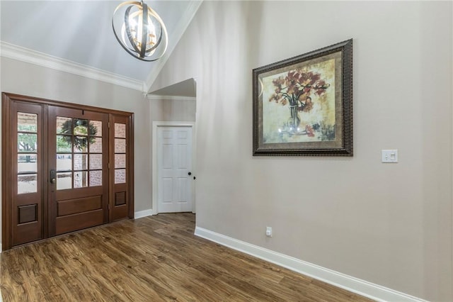 foyer entrance with a notable chandelier, hardwood / wood-style flooring, vaulted ceiling, and ornamental molding