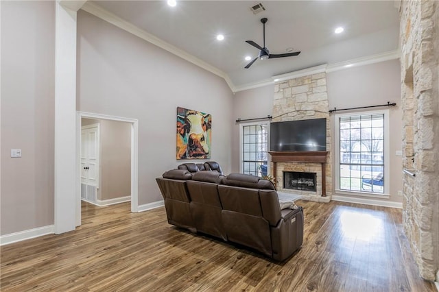 living room featuring high vaulted ceiling, a stone fireplace, hardwood / wood-style flooring, ceiling fan, and ornamental molding