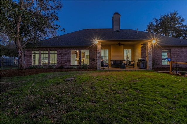 rear view of house with a patio, ceiling fan, and a lawn