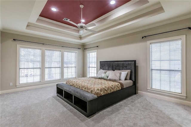 carpeted bedroom with a tray ceiling, ceiling fan, and ornamental molding