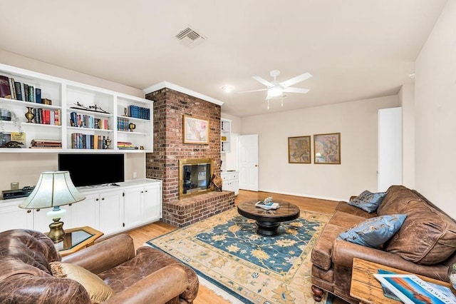 living room featuring light hardwood / wood-style flooring, a fireplace, and ceiling fan