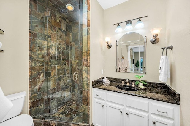 bathroom with a shower with door, vanity, and toilet