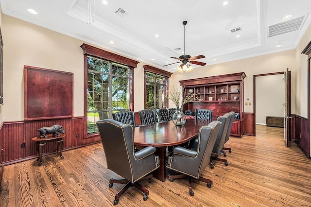 dining room featuring crown molding, a tray ceiling, and light hardwood / wood-style flooring