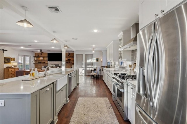 kitchen featuring french doors, appliances with stainless steel finishes, open floor plan, a sink, and wall chimney range hood