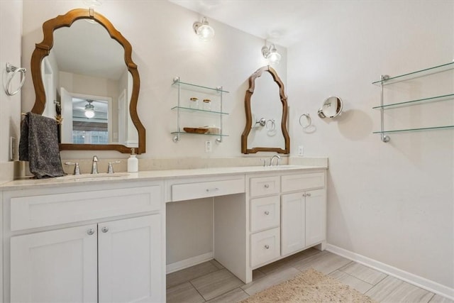 full bath featuring double vanity, baseboards, and a sink