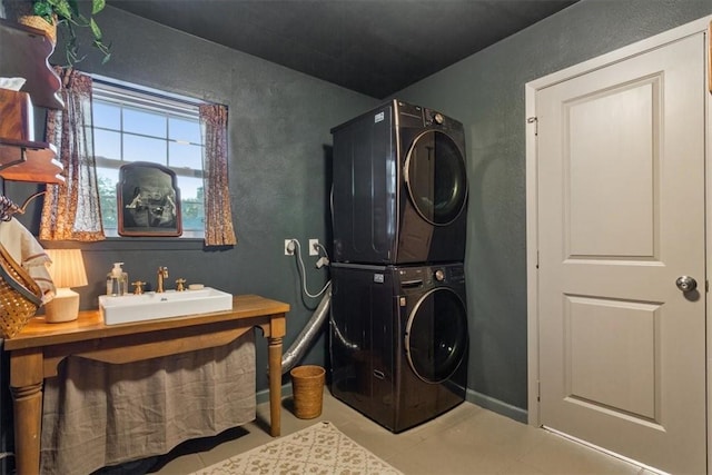 laundry area featuring stacked washing maching and dryer, a sink, and baseboards