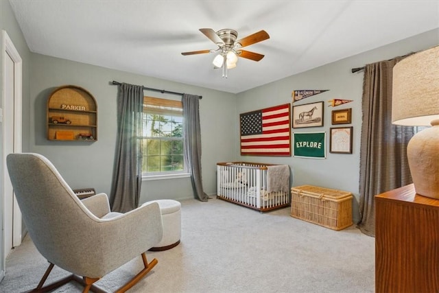 bedroom with a nursery area, carpet floors, and a ceiling fan