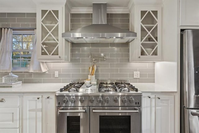 kitchen with backsplash, wall chimney exhaust hood, stainless steel appliances, and light countertops