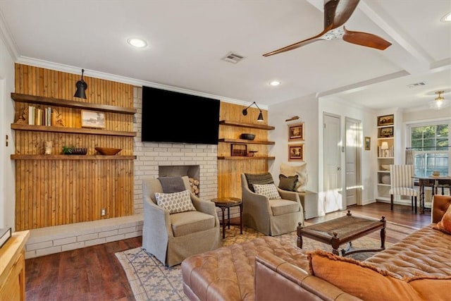 living area featuring crown molding, visible vents, a ceiling fan, a brick fireplace, and wood finished floors