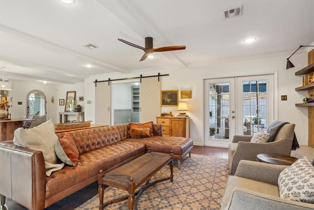 living room with a barn door, beamed ceiling, visible vents, and a ceiling fan