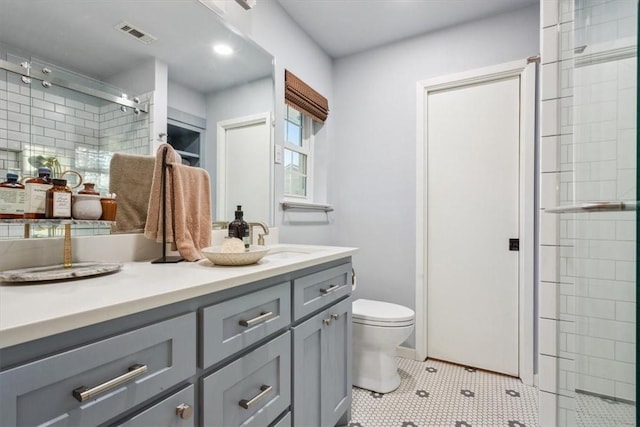 bathroom featuring visible vents, toilet, tile patterned floors, vanity, and a shower stall