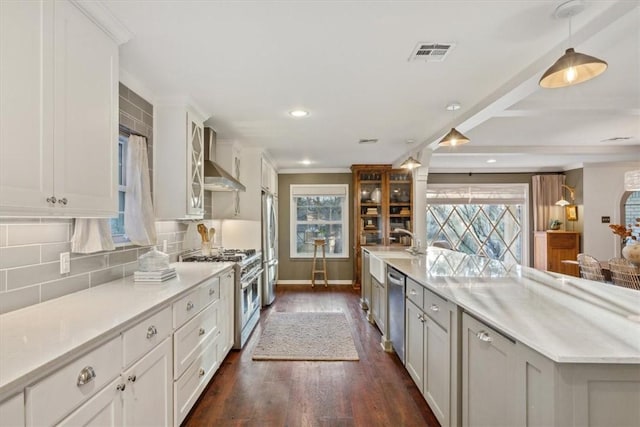 kitchen featuring stainless steel appliances, visible vents, decorative backsplash, wall chimney exhaust hood, and glass insert cabinets