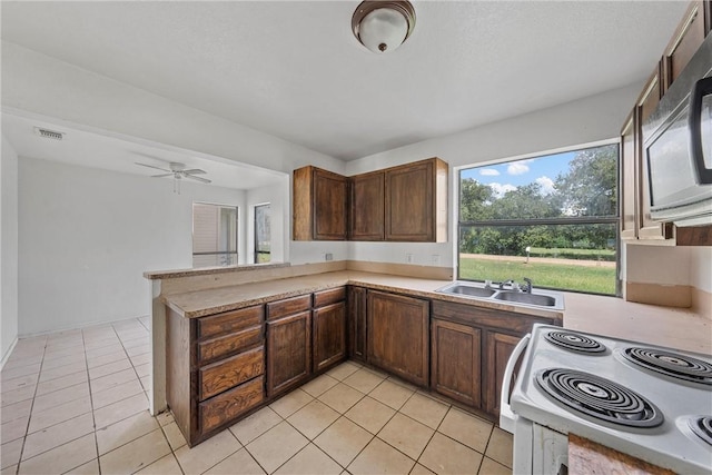 kitchen with kitchen peninsula, ceiling fan, sink, white electric stove, and light tile patterned flooring