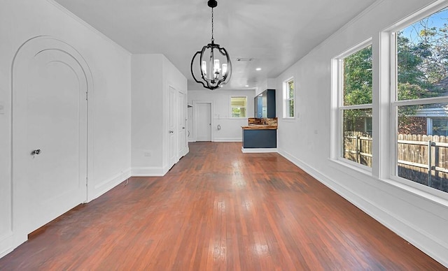 interior space featuring dark hardwood / wood-style floors, crown molding, a wealth of natural light, and an inviting chandelier