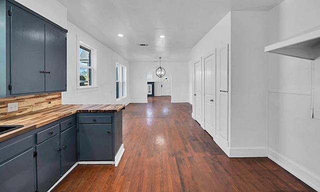 kitchen featuring decorative backsplash, pendant lighting, dark hardwood / wood-style floors, and wood counters