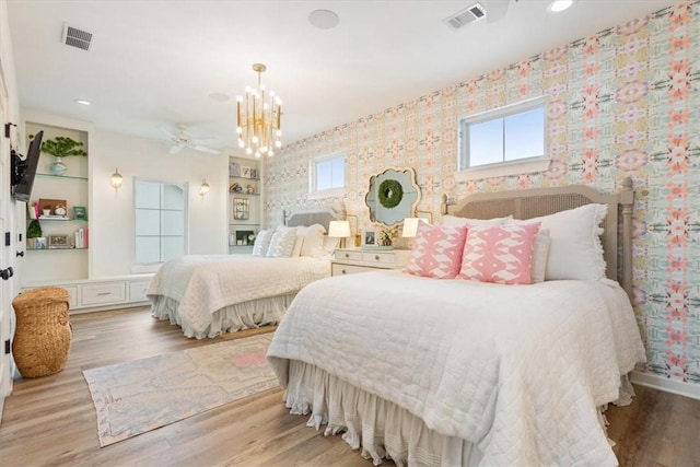 bedroom featuring multiple windows, an inviting chandelier, and light hardwood / wood-style floors