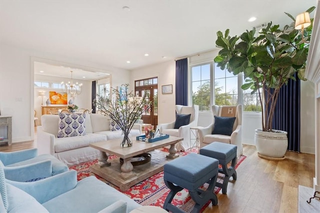 living room featuring an inviting chandelier, a wealth of natural light, and light hardwood / wood-style flooring