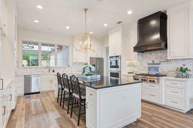 kitchen featuring custom exhaust hood, white cabinets, and appliances with stainless steel finishes