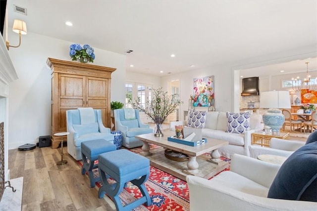 living room with french doors, an inviting chandelier, and light hardwood / wood-style floors