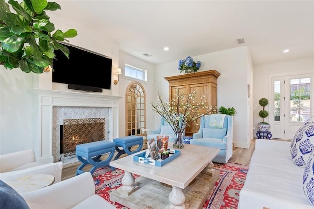 living room with wood-type flooring and a tiled fireplace