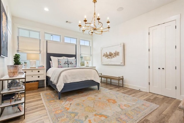 bedroom featuring a notable chandelier, light hardwood / wood-style floors, and a closet