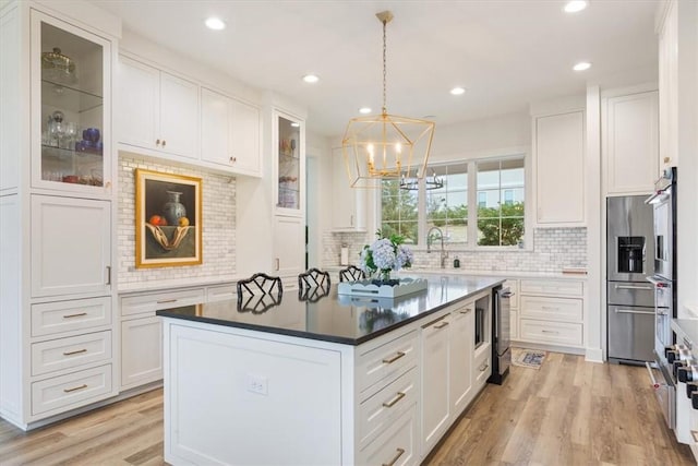 kitchen featuring light wood-type flooring, white cabinetry, pendant lighting, and a center island