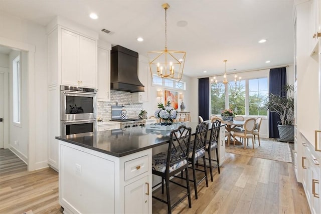 kitchen with stainless steel appliances, white cabinets, pendant lighting, a center island, and custom exhaust hood