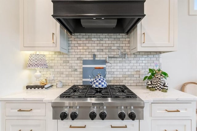 kitchen with stainless steel gas stovetop, custom exhaust hood, light stone countertops, and white cabinets