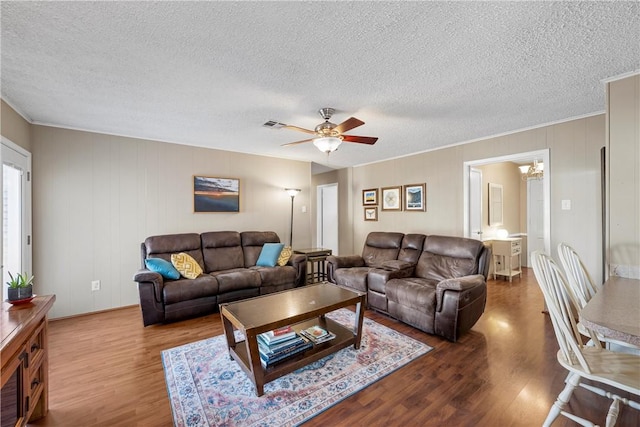 living room with hardwood / wood-style flooring, ceiling fan with notable chandelier, and a textured ceiling