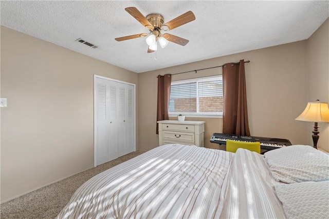 carpeted bedroom featuring ceiling fan, a closet, and a textured ceiling