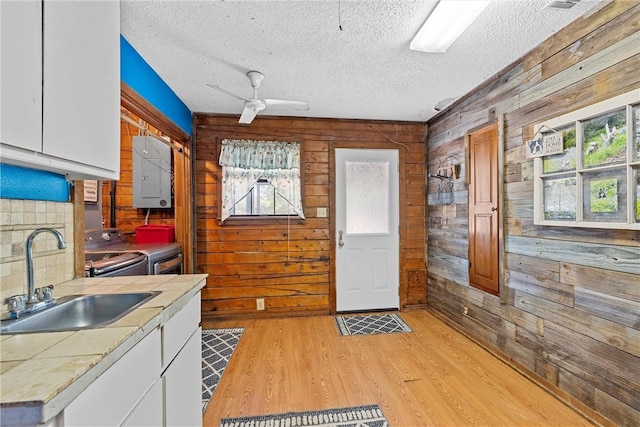 kitchen featuring separate washer and dryer, wood walls, plenty of natural light, and sink