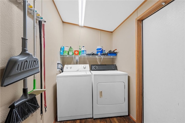 clothes washing area featuring washing machine and dryer, dark wood-type flooring, and ornamental molding