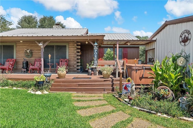 rear view of property with a yard, covered porch, and a hot tub