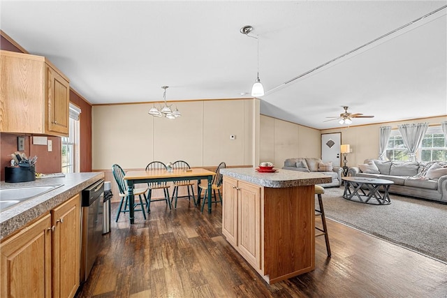 kitchen featuring dark hardwood / wood-style flooring, stainless steel dishwasher, pendant lighting, a kitchen island, and ceiling fan with notable chandelier