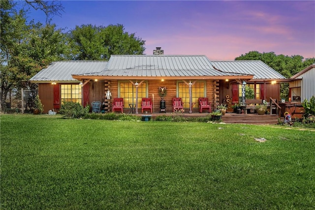 back house at dusk with a lawn and a porch