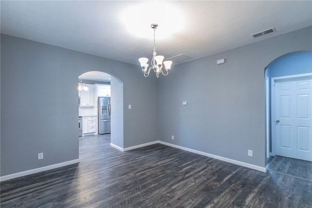 unfurnished room featuring dark wood-type flooring and an inviting chandelier