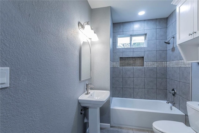 bathroom with tile patterned floors, tiled shower / bath, and toilet