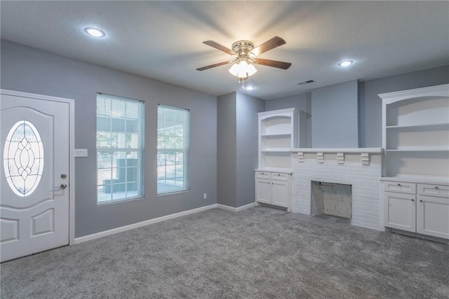 unfurnished living room featuring carpet, a textured ceiling, a fireplace, and ceiling fan