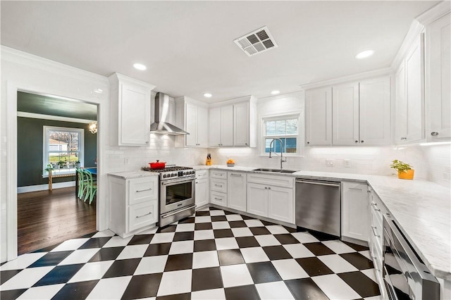 kitchen featuring white cabinetry, wall chimney range hood, sink, and appliances with stainless steel finishes