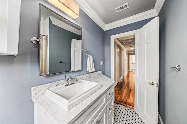 bathroom featuring hardwood / wood-style flooring, crown molding, and vanity